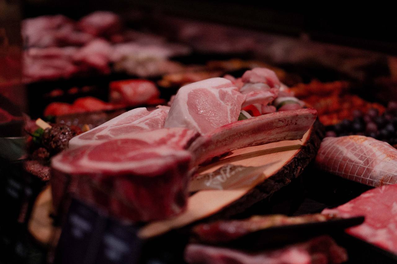 Frische Koteletts und Braten in der Fleischtheke, angerichtet auf einer Holzscheibe