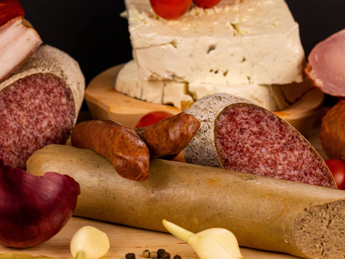 Wurstspezialitäten aus eigener Herstellung: Salami, Mettenden, Leberwurst und Speck auf einem Holzbrett